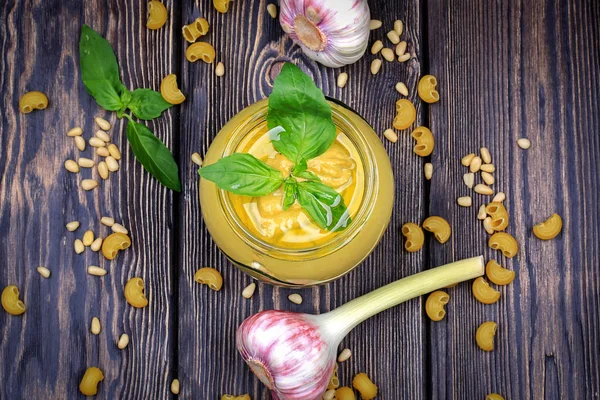 Pesto soslu makarna üzerine koyu ahşap arka plan için. Sedir fındık, fesleğen, sarımsak, zeytinyağı, peynir