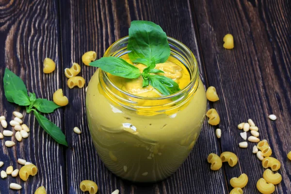 Pesto soslu makarna üzerine koyu ahşap arka plan için. Sedir fındık, fesleğen, sarımsak, zeytinyağı, peynir