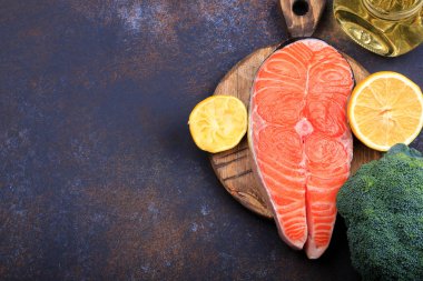 Koyu arka plan üstten görünüm üzerinde limon ve zeytin yağı ile Çiğ somon biftek.