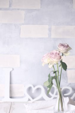 Tuğladan bir arka planda aşk sözcüğüyle narin güller