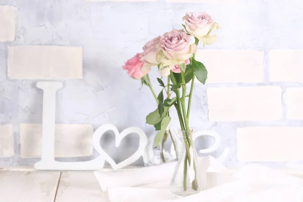 Delicadas rosas em um fundo de tijolo com a palavra amor — Fotografia de Stock