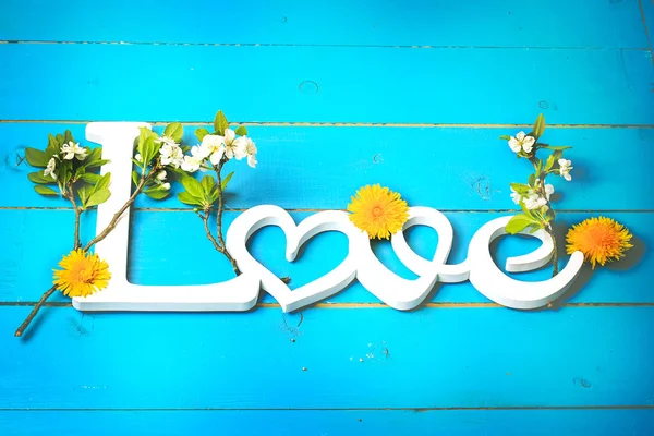 Слово любовь на деревянном фоне с весенними цветами. День Святого Валентина — стоковое фото