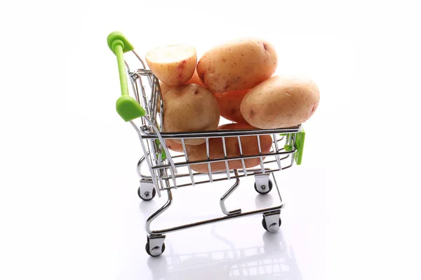 Batatas cruas em um carrinho de compras isolado em fundo branco — Fotografia de Stock