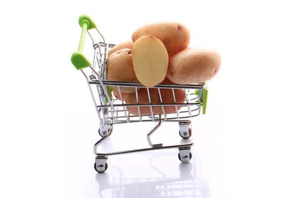 Batatas cruas em um carrinho de compras isolado em fundo branco — Fotografia de Stock