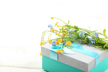 Beyaz ahşap arka planda hediye kutusunda yabani çiçekler