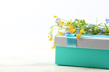 Beyaz ahşap arka planda hediye kutusunda yabani çiçekler