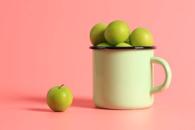 Yeşil kiraz eriği pembe arka planda bir diş minesi bardağında. Yaratıcı minimalist stil. sağlıklı yiyecekler