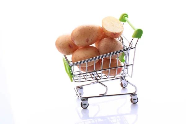 Batatas cruas em um carrinho de compras isolado em fundo branco — Fotografia de Stock