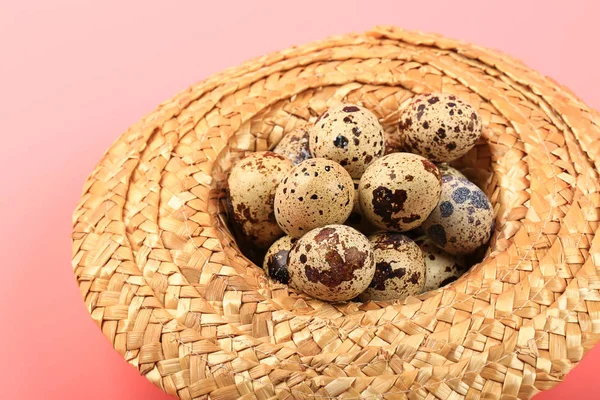 Huevos de codorniz en un sombrero de paja sobre un fondo rosa — Foto de Stock