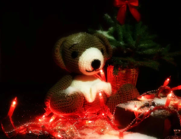 Рождественский фон вязаная медвежья игрушка, ель с красным луком и грецкими орехами на коричневом фоне — стоковое фото