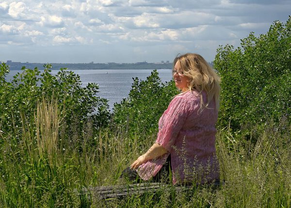 A young 40 years old fat woman sits on a bench in a clearing above the Volga River Russia 