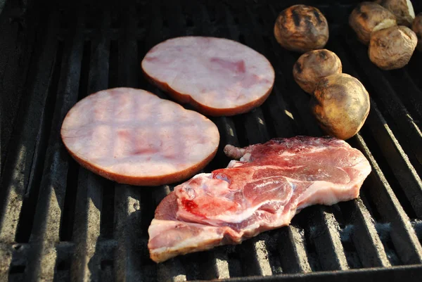 Asar a la parrilla un chuleta de cordero, filetes de jamón y patatas enteras — Foto de Stock