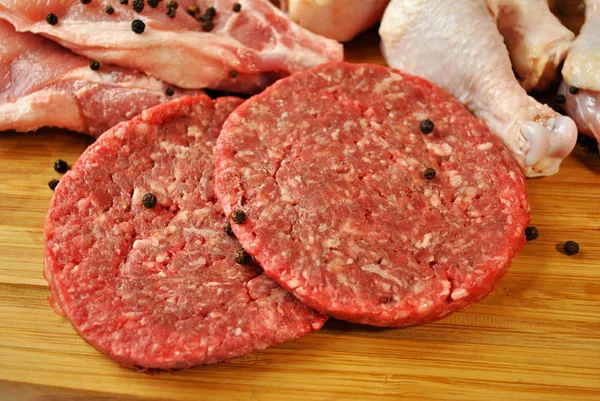 Hambúrgueres de carne crua com pimenta integral — Fotografia de Stock