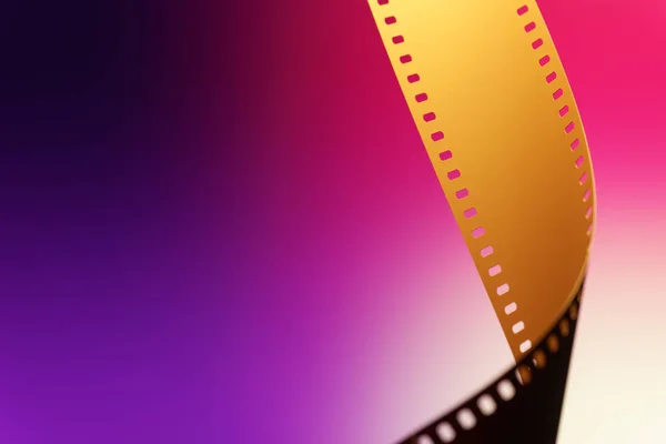 Camera negative film. Selective focus on film perforation. Unprocessed color motion picture film. Industry symbol for shooting process, photochemical laboratory process and film archive technology. Color gradient background.