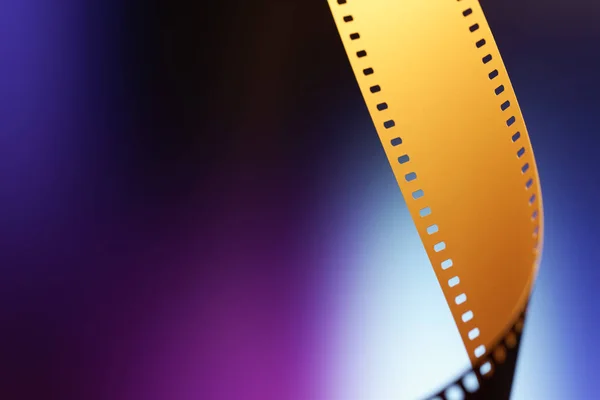 Camera negative film. Selective focus on film perforation. Unprocessed color motion picture film. Industry symbol for shooting process, photochemical laboratory process and film archive technology. Color gradient background.