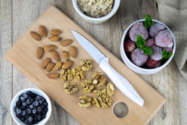 Bir kasede yulaf ezmesi ve müsli, ahşap zemin üzerinde taze böğürtlen ve süt ve üzerinde bıçak olan bir tahta.