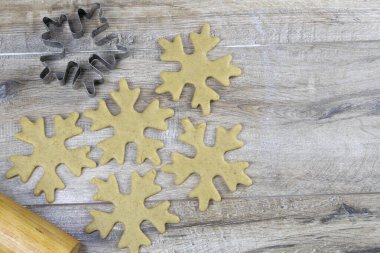Güzel bir ağaçlık masada kar taneleri şeklinde zencefilli Noel kurabiyeleri ve kar taneleri kesmek için bir form.