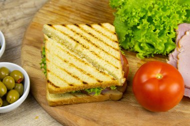 Classic club sandwich with ham and bacon on a wooden board