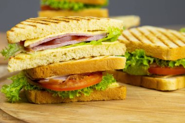 Classic club sandwich with ham and bacon on a wooden board