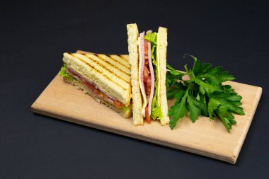 Tahta bir tahtanın üzerinde birkaç dilim beyaz ekmek. Sandviç peynirli ve jambonlu.