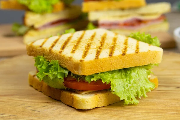 Classic club sandwich with ham and bacon on a wooden board — Stock Photo, Image