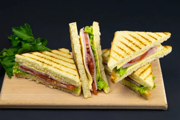 Sandwich de varias rebanadas de pan blanco en una tabla de madera. El relleno del sándwich consiste en queso y jamón — Foto de Stock