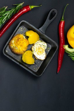 Siyah arka planda kalp şeklinde bıldırcın yumurtaları olan küçük siyah bir tava.