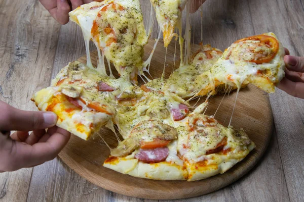 Люди кидають шматочки піци з моцарелою. салямі та помідори — стокове фото