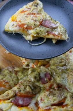 A slice of pizza on a plate in the background of pizza on the board