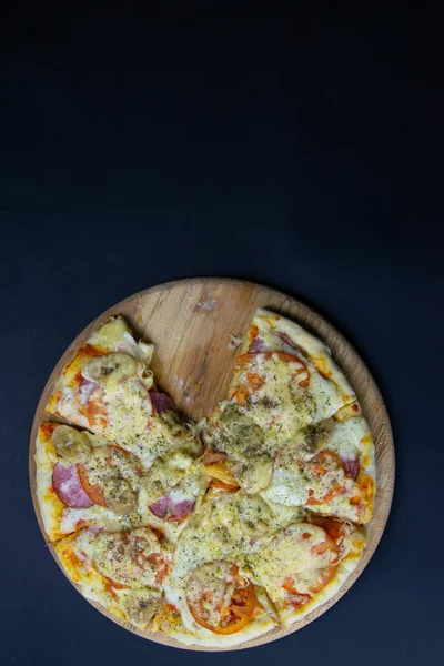 Піца з салямі, моцарелою, помідорами, бананами стоїть на дерев'яній дошці . — стокове фото