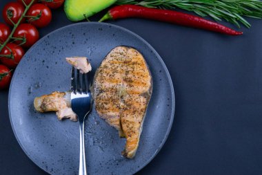 Fresh raw salmon steaks with vegetables and spices: rosemary, tomatoes, peppers, basil, lemon and olive oil