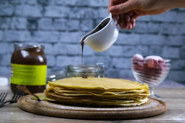 Panqueques con mantequilla y chocolate en una tabla redonda de madera —  Fotos de Stock