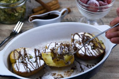 Ballı ve tarçınlı karamelli elmalar hafif ahşap arka planda kil kasede.