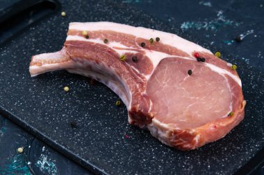 Çiğ biftek, biberiyeyle birlikte mermer bir tahtanın üzerinde duruyor.