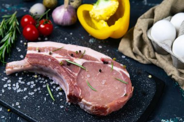 Biberiye, mısır, yumurta ve dolmalık biberin yanındaki kemiklerde çiğ domuz eti. Mermer çiftlik eti.