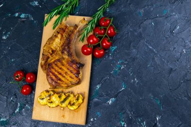 Kemiğin üzerinde ızgara domuz bifteği var. Izgarada kızartılmış mantarların yanında ahşap bir tahtanın üzerinde duruyor..