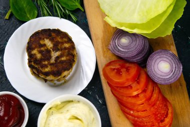 Ev yapımı hamburger malzemeleri: domates, mor soğan, lahana köftesi, beyaz sarımsak ve kırmızı sos.