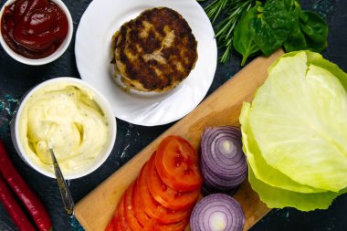 Ev yapımı hamburger malzemeleri: domates, mor soğan, lahana köftesi, beyaz sarımsak ve kırmızı sos.