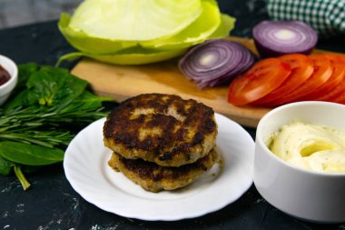 Ev yapımı hamburger malzemeleri: domates, mor soğan, lahana köftesi, beyaz sarımsak ve kırmızı sos.