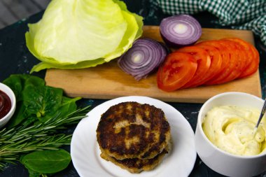 Ev yapımı hamburger malzemeleri: domates, mor soğan, lahana köftesi, beyaz sarımsak ve kırmızı sos.