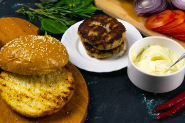 Ev yapımı hamburger malzemeleri: susamlı çörek, domates, mor soğan, lahana köftesi.