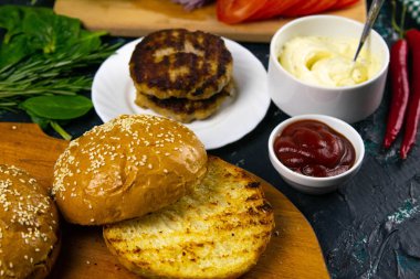 Ev yapımı hamburger malzemeleri: susamlı çörek, domates, mor soğan, lahana köftesi.