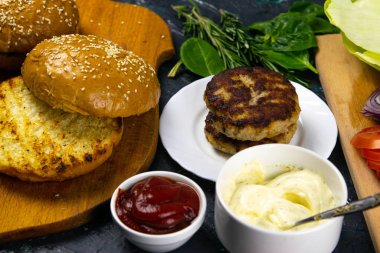 Ev yapımı hamburger malzemeleri: susamlı çörek, domates, mor soğan, lahana köftesi.