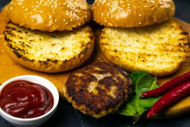 Ev yapımı hamburger malzemeleri: susamlı çörek, domates, mor soğan, lahana köftesi.