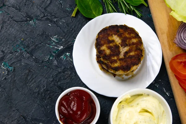 Ev yapımı hamburgerler köfte, beyaz sarımsak ve kırmızı sos klasik ahşap tabağa dizilmiş..