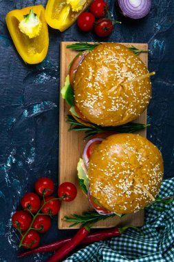 İki ev yapımı mantarlı sığır burger, mikro yeşiller, ahşap kesim tahtasındaki kırmızı soğan.