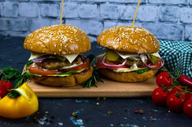 İki ev yapımı mantarlı sığır burger, mikro yeşiller, ahşap kesim tahtasındaki kırmızı soğan.