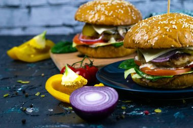 İki ev yapımı mantarlı sığır burger, mikro yeşiller, ahşap kesim tahtasındaki kırmızı soğan.