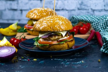 İki ev yapımı mantarlı sığır burger, mikro yeşiller, ahşap kesim tahtasındaki kırmızı soğan.