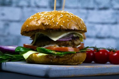 İki ev yapımı mantarlı sığır burger, mikro yeşiller, ahşap kesim tahtasındaki kırmızı soğan.